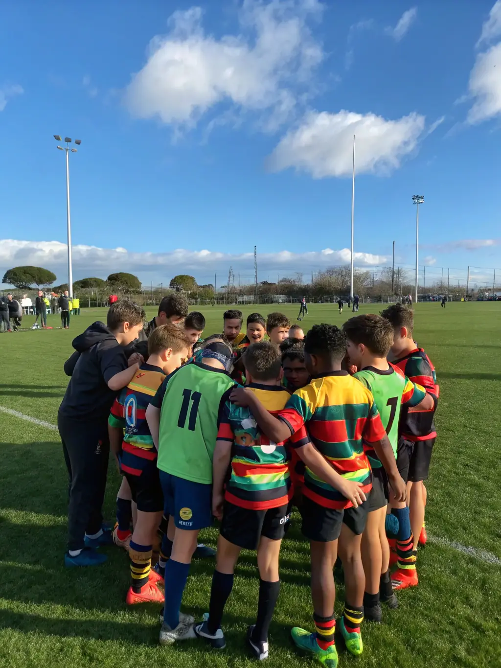 A dynamic action shot of young rugby players participating in a training session, focusing on teamwork and skill development, set against a backdrop of a sunny rugby field.